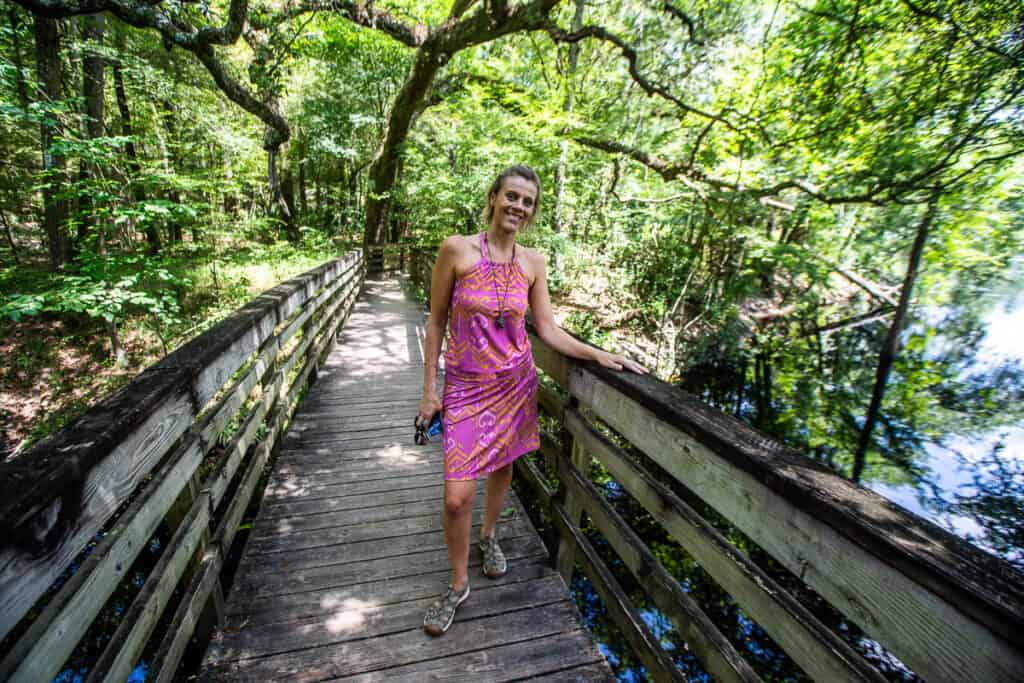 Woman walking across a bridge on a trail.