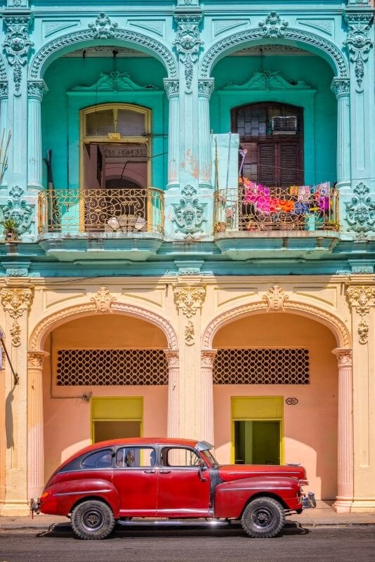 red car in front of colorful building in cuba