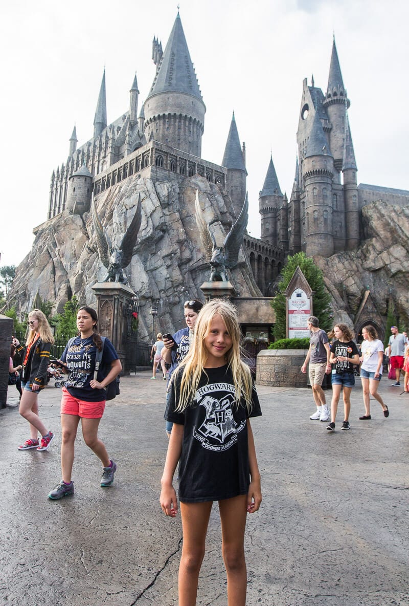 young girl standing in front of Hogwarts Castle at The Wizarding World of Harry Potter in Universal Orlando