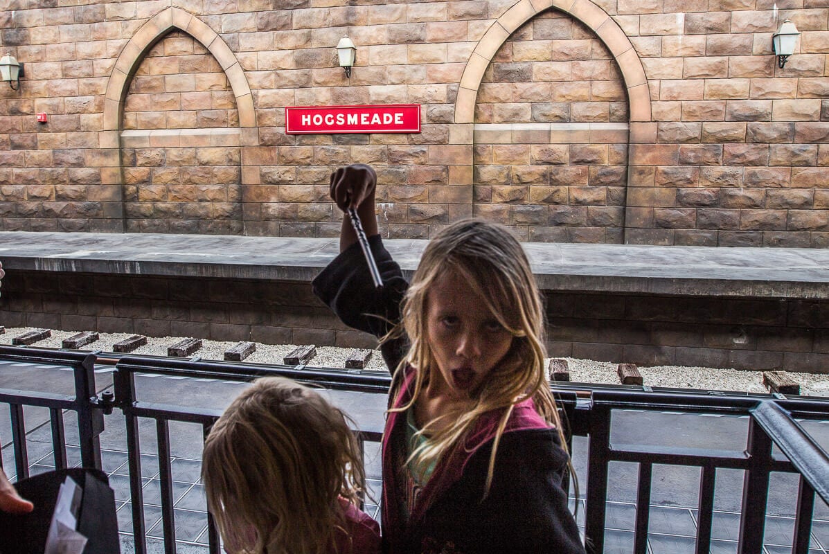 girl holding up wand on station waiting for hogwarts train